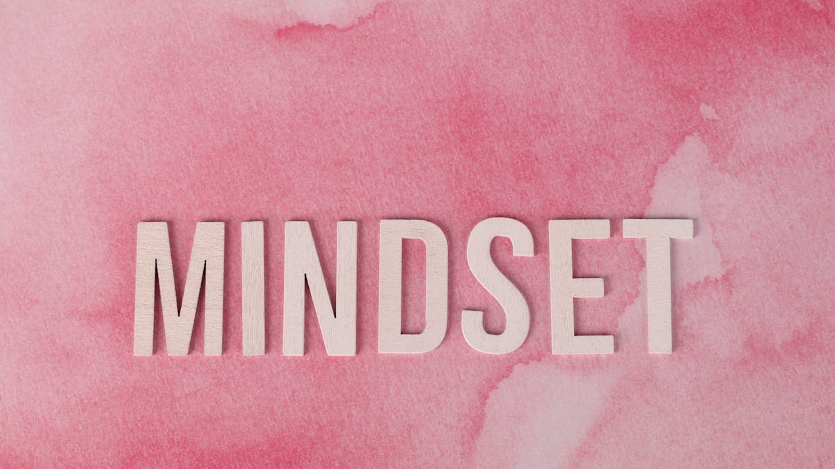 Wooden letters spelling 'MINDSET' on a textured pink background, symbolizing motivation.
